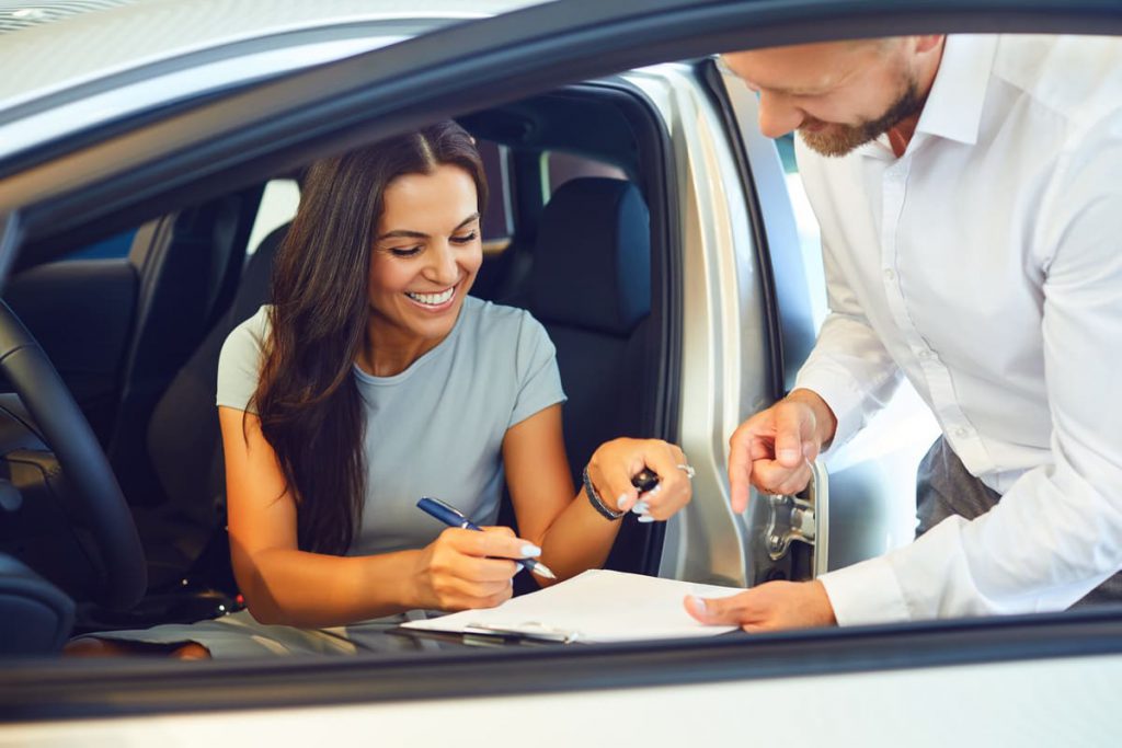 Femme signant un contrat avec un concessionnaire